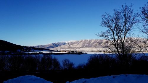 Scenic view of frozen lake against clear blue sky