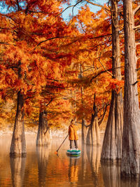 Rear view of woman in boat in lake during autumn