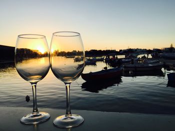 Wineglasses at lakeshore against sky