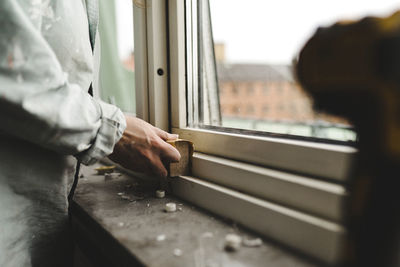 Womans hand sanding window frame