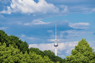 Low angle view of communications tower against cloudy sky