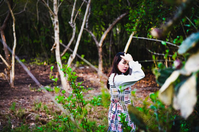 Woman standing by tree in forest