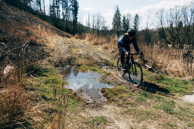 Full length of woman riding bicycle in forest