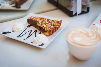 High angle view of pastry with cappuccino served on table