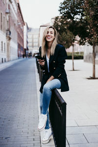 Portrait of smiling young woman on footpath in city