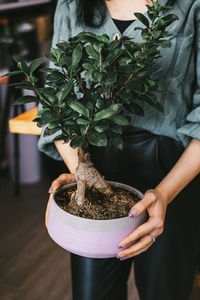 Midsection of woman holding potted plant