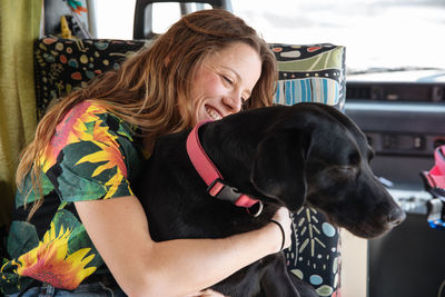 Woman embracing dog in camper van