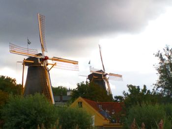 Windmill against cloudy sky