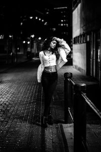 Woman standing on street in city at night