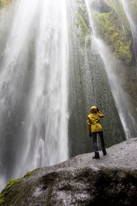 Bright hiker at scenic canyon waterfall with green mossy walls