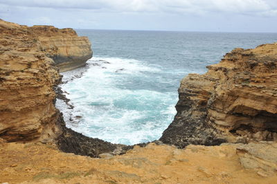 Rock formation on sea shore against sky