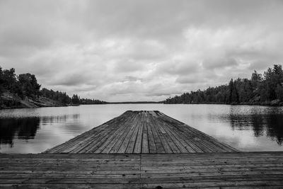 Pier over lake against cloudy sky