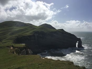 Scenic view of sea by cliff against sky