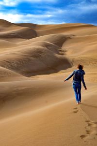 Full length of woman walking on sand dune