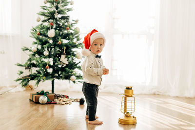A little kid in a christmas hat on the background of a christmas tree. christmas themed picture