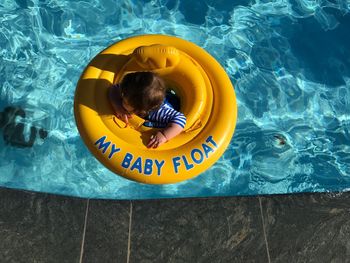 High angle view of baby boy on inflatable ring in swimming pool