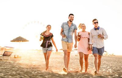 Full length of happy friends walking at beach