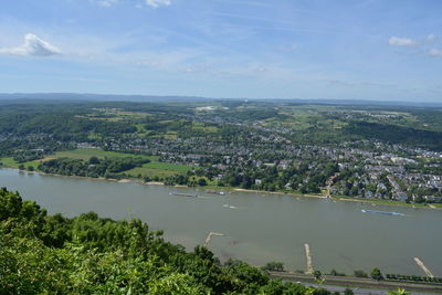 Scenic view of river by cityscape against sky