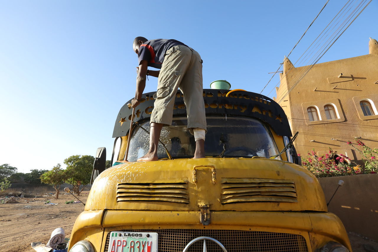 LOW ANGLE VIEW OF MAN AGAINST BLUE SKY