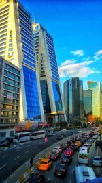 Vehicles on road in city against blue sky