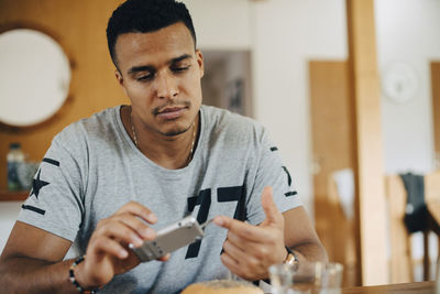 Mid adult man using glaucometer while having breakfast at home