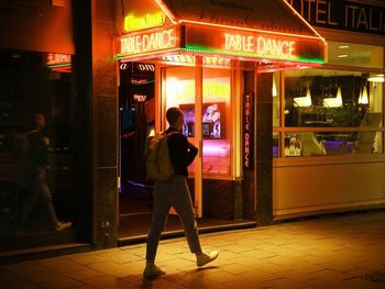 Full length of woman standing in illuminated city at night