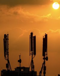 Low angle view of silhouette dishes against orange sky