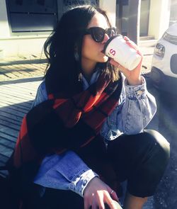 Portrait of young woman wearing sunglasses sitting outdoors