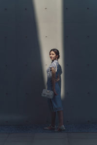 Side view of woman standing against wall