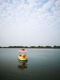 Boat floating on lake against sky