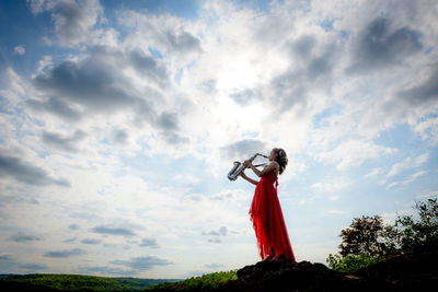 Low angle view of person holding sculpture against sky