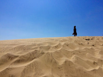 Man on sand at beach against clear blue sky