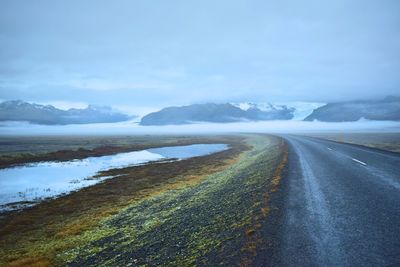 Scenic view of road by mountains against sky