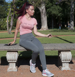 Young woman sitting on bench in park