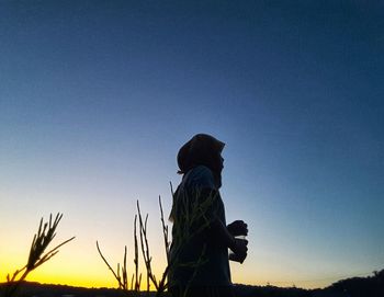 Silhouette woman standing on field against clear sky during sunset