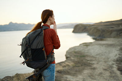 Young woman standing on shore against sky