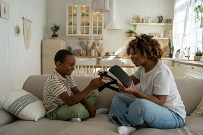 Young woman using digital tablet while sitting on sofa at home