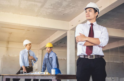 Young engineer against colleagues working at construction site