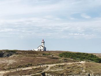 Lighthouse by building against sky