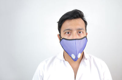 Portrait of young man covering face against white background