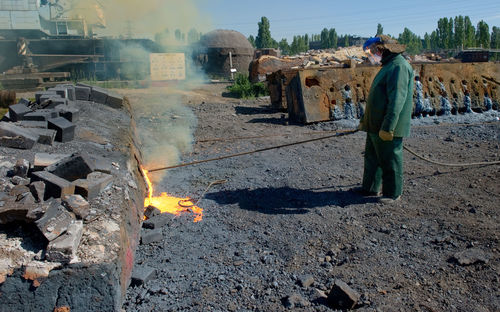 Worker melting metal while standing on abandoned road