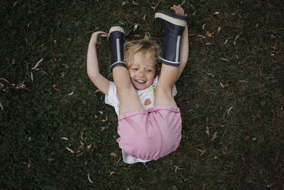 High angle view of playful girl lying on grassy field at park