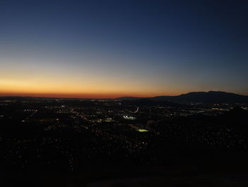 High angle view of illuminated city against sky at sunset