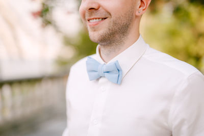 Midsection of groom wearing bow tie outdoors