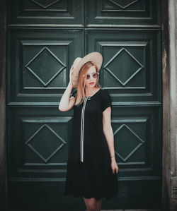 Fashionable young woman standing against door