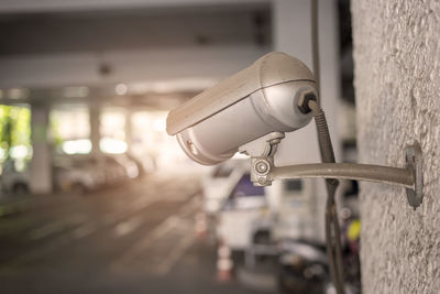 Close-up of surveillance camera on wall at parking lot