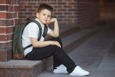 Portrait of boy sitting against wall