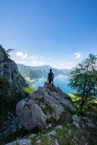 Hiking man on a rock with lake on the background