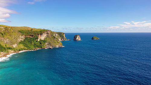 Blue sea washes rocky mountains covered forest. separate rocks in water. nusa penida, indonesia