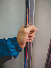 Close-up of hand holding metal against wall